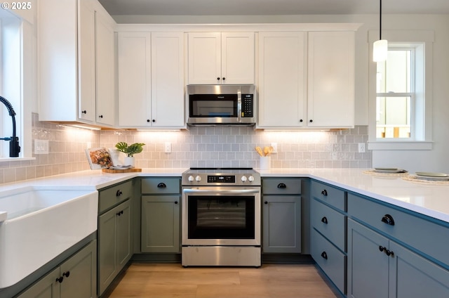 7265 SE Duke St Unit 2, Portland, OR 97206 - kitchen featuring appliances with stainless steel finishes, a sink, light countertops, and white cabinetry