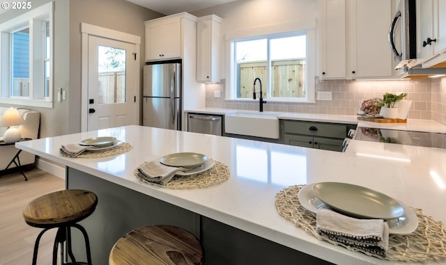 7265 SE Duke St Unit 2, Portland, OR 97206 - kitchen with stainless steel appliances, a sink, a breakfast bar area, backsplash, and light countertops