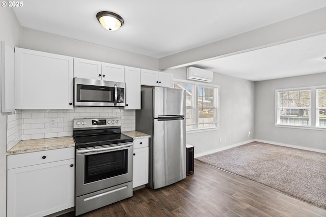 kitchen featuring plenty of natural light, stainless steel appliances, tasteful backsplash, white cabinets, and an AC wall unit