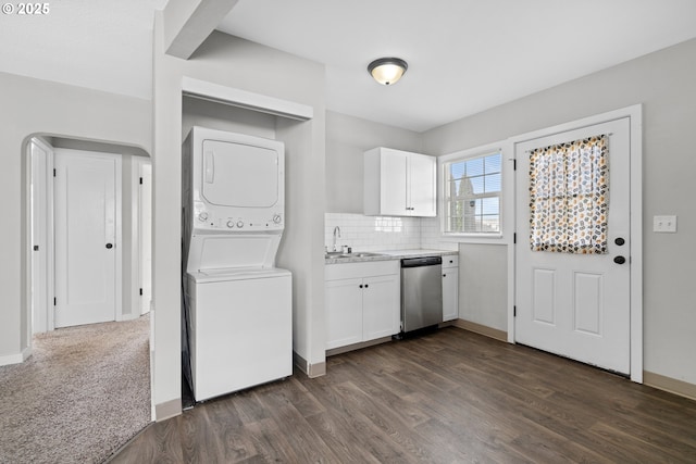 laundry area featuring stacked washing maching and dryer, sink, and dark hardwood / wood-style floors