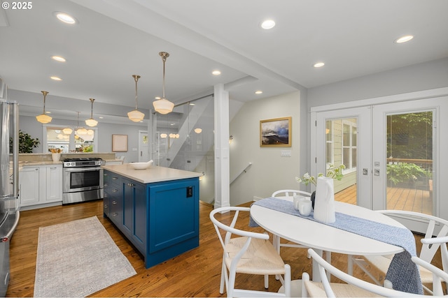7928 SE 21st Ave, Portland, OR 97202 - kitchen with stainless steel gas range oven, blue cabinetry, french doors, wood finished floors, and plenty of natural light