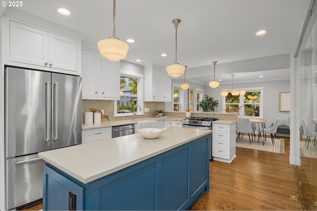 7928 SE 21st Ave, Portland, OR 97202 - kitchen featuring stainless steel appliances, a peninsula, light countertops, blue cabinetry, and decorative backsplash