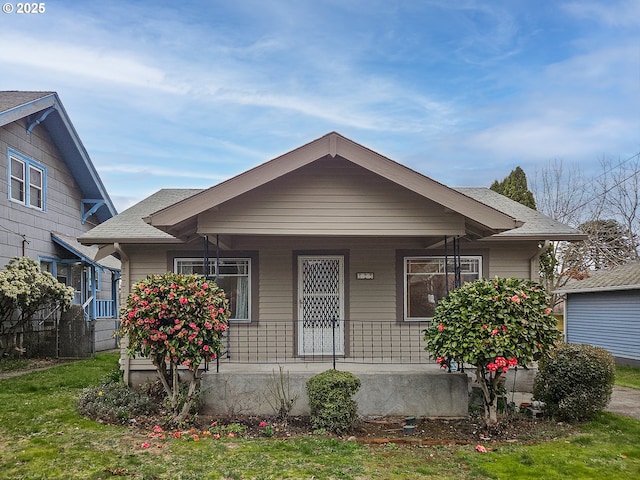 bungalow-style home featuring covered porch and roof with shingles