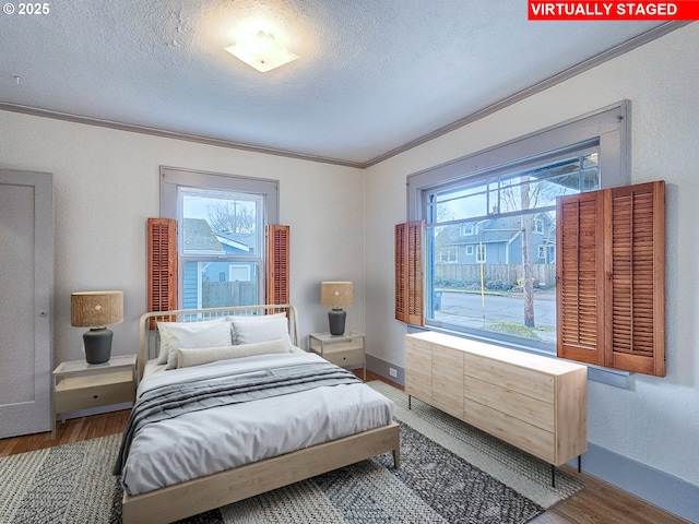 bedroom featuring crown molding, baseboards, wood finished floors, and a textured ceiling