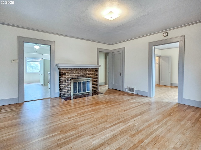 unfurnished living room with visible vents, a textured ceiling, and wood finished floors