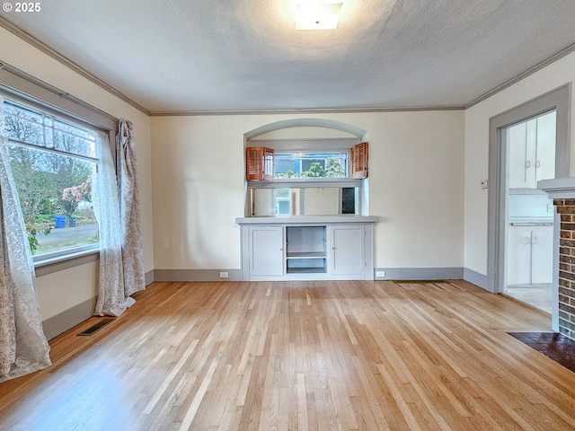 unfurnished living room featuring visible vents, a brick fireplace, crown molding, light wood-type flooring, and a textured ceiling