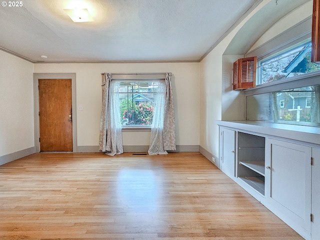 interior space featuring visible vents, baseboards, ornamental molding, a textured ceiling, and light wood-type flooring