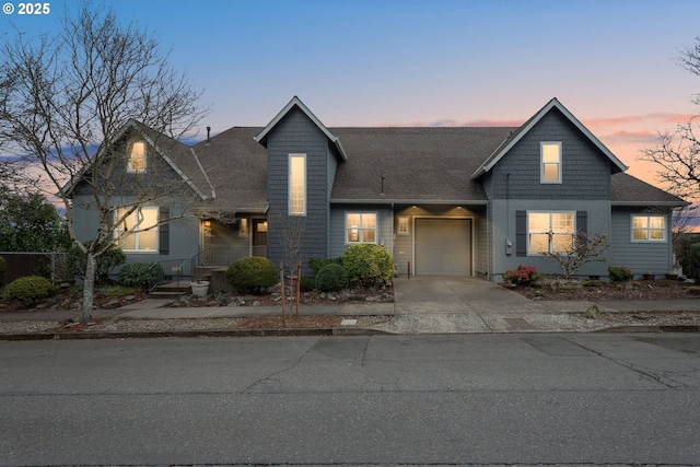 view of front of property featuring concrete driveway, a shingled roof, and an attached garage