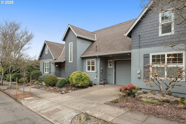 view of front facade featuring driveway, a shingled roof, and an attached garage