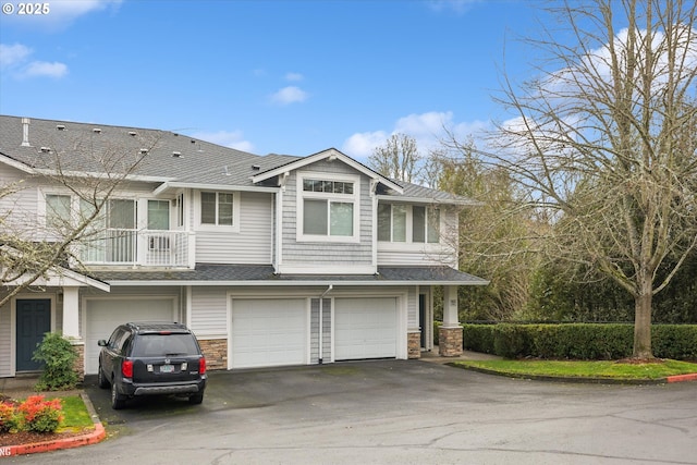 view of front of property featuring a garage, stone siding, driveway, and a shingled roof