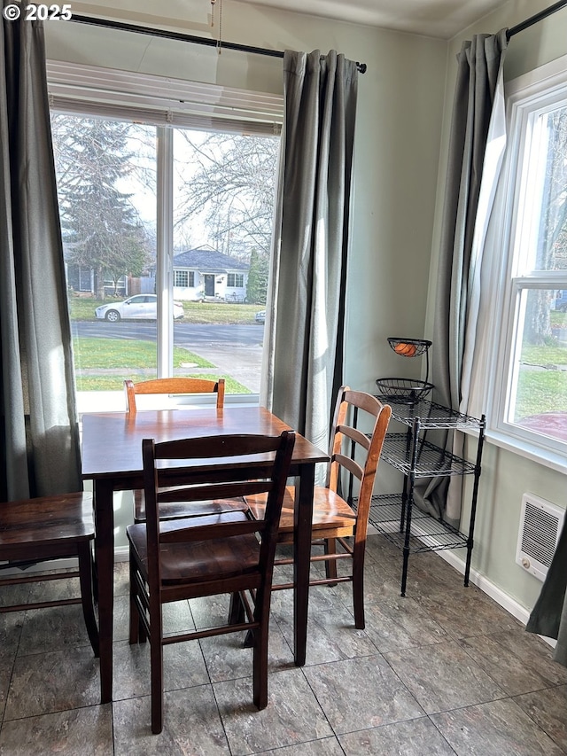 dining space featuring baseboards, an AC wall unit, and stone finish floor