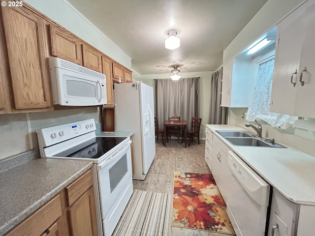 kitchen with brown cabinetry, white appliances, ceiling fan, and a sink