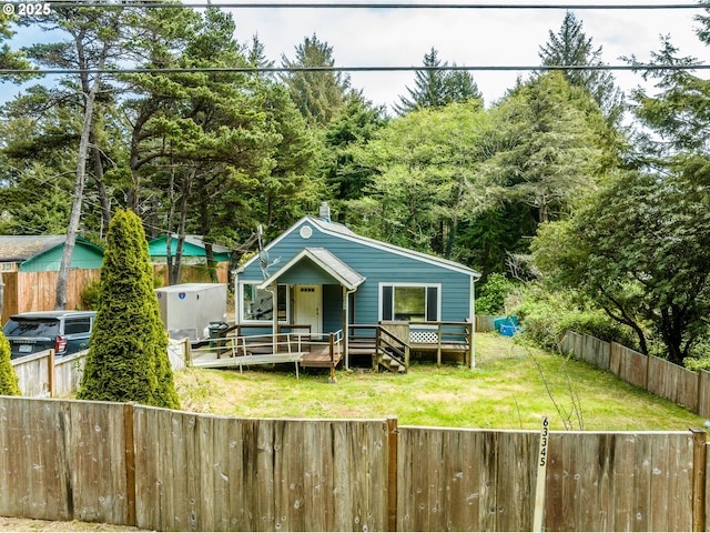 rear view of house with a fenced backyard, a yard, and a deck