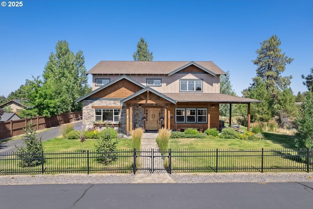 view of front facade with covered porch, a fenced front yard, a front lawn, and stone siding