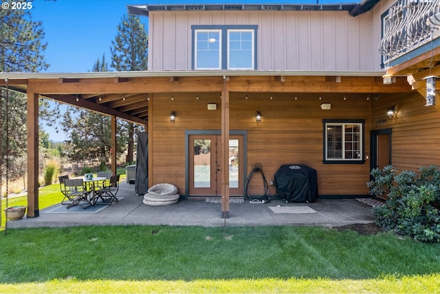 back of house featuring a lawn, a patio, and board and batten siding