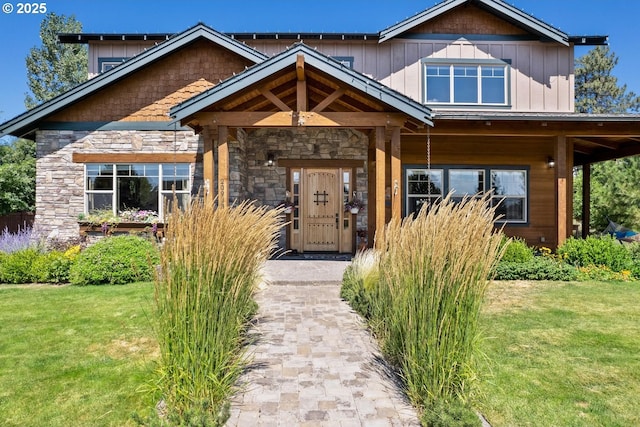 view of front of house with covered porch, stone siding, and a front lawn