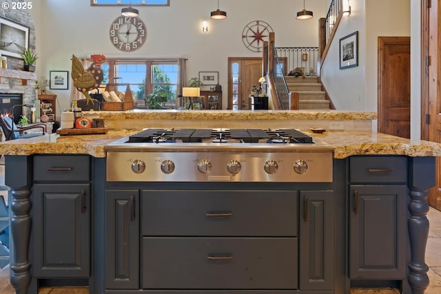 kitchen with light stone counters, open floor plan, a stone fireplace, and stainless steel gas stovetop