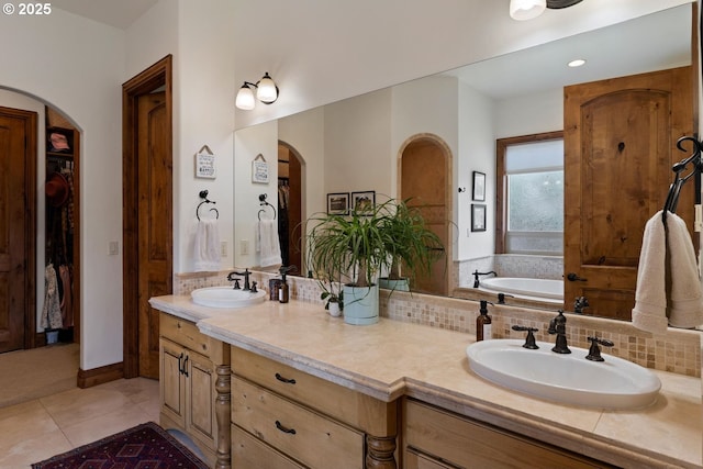 bathroom with double vanity, tile patterned floors, a sink, and a garden tub