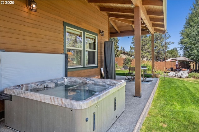 view of patio / terrace with a hot tub and fence