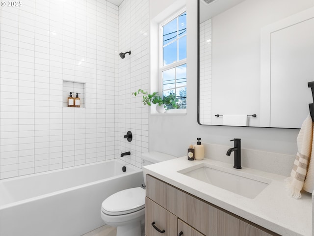 full bathroom featuring vanity, tiled shower / bath, and toilet