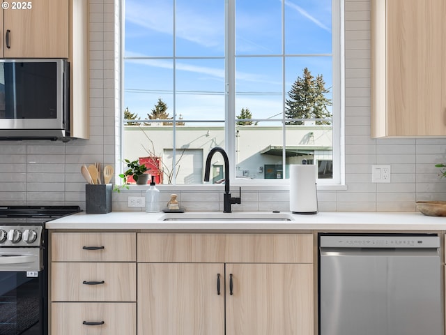 kitchen with sink, stainless steel appliances, and light brown cabinetry