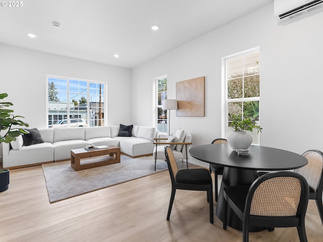 dining space featuring an AC wall unit, a wealth of natural light, and light hardwood / wood-style floors