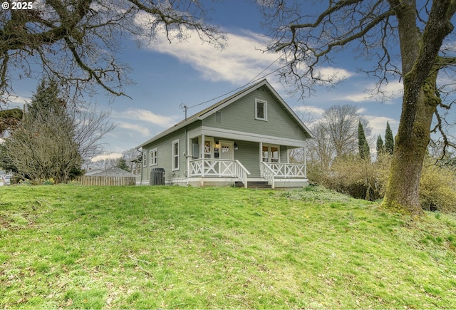 view of front of home with a porch, fence, central AC unit, and a front lawn