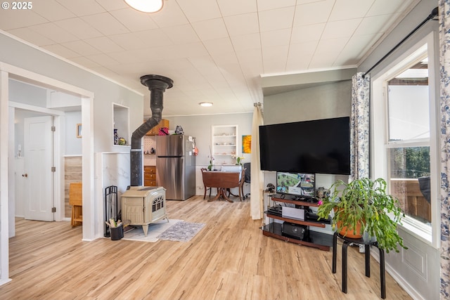 living room with a wood stove, light wood-style flooring, and crown molding