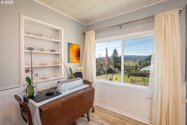 home office featuring built in features, ornamental molding, and light wood finished floors