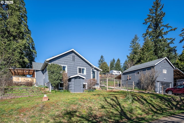 rear view of property featuring an outbuilding, a yard, a storage shed, and fence