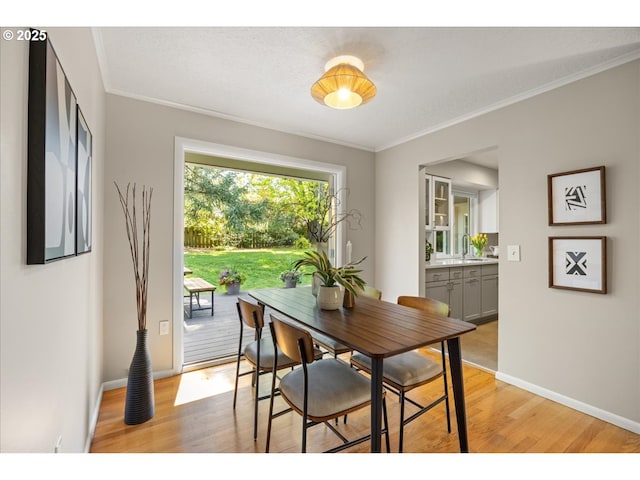 dining space featuring baseboards, ornamental molding, and light wood-style flooring
