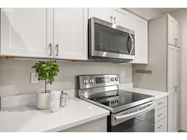 kitchen featuring white cabinets, appliances with stainless steel finishes, and light stone counters