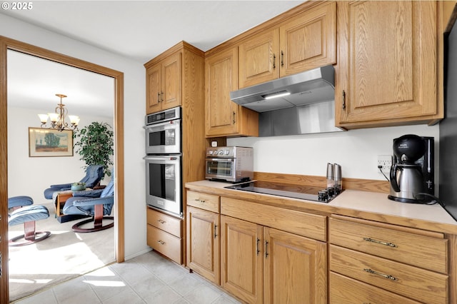 kitchen featuring stainless steel double oven, a toaster, black electric stovetop, an inviting chandelier, and under cabinet range hood