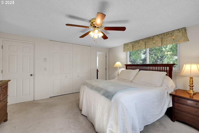 bedroom with a ceiling fan, a textured ceiling, light colored carpet, and a closet