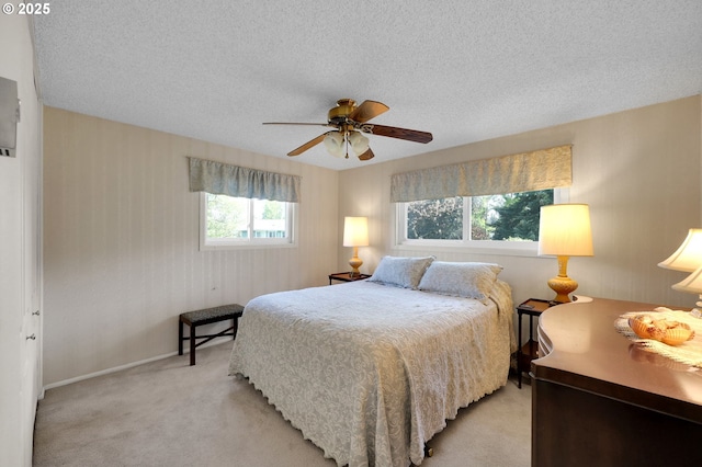 bedroom with baseboards, light carpet, a ceiling fan, and a textured ceiling