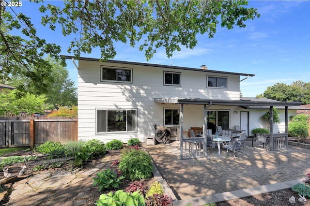 back of property featuring fence, outdoor dining space, a chimney, and a patio area