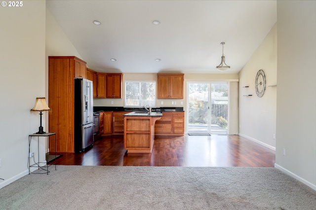 kitchen featuring vaulted ceiling, a kitchen island, high quality fridge, sink, and a breakfast bar area