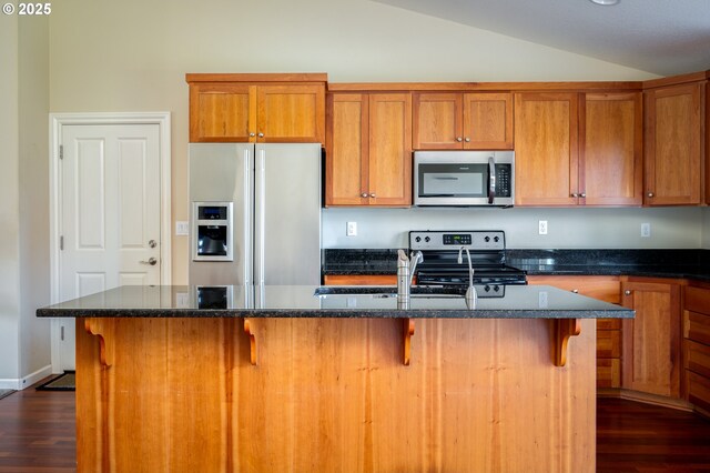 kitchen with lofted ceiling, stainless steel appliances, a kitchen breakfast bar, and a center island with sink