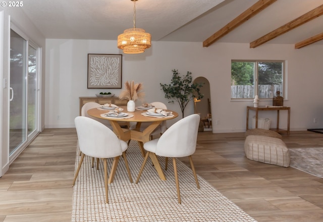 dining space featuring beamed ceiling, arched walkways, light wood-style floors, baseboards, and a chandelier