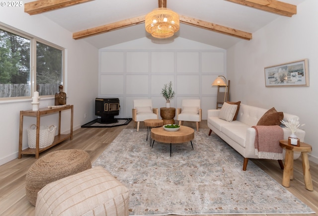 living room with wood finished floors, baseboards, an inviting chandelier, lofted ceiling with beams, and a wood stove