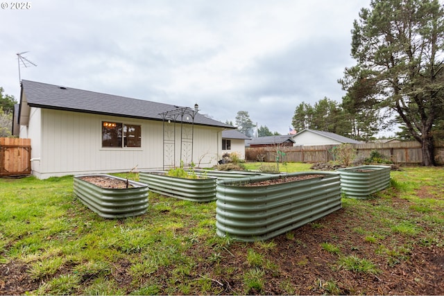 rear view of property with a yard, a vegetable garden, and fence