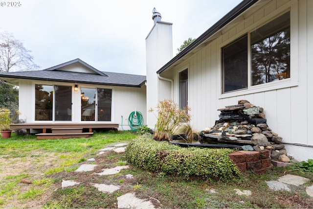 exterior space with roof with shingles and a chimney