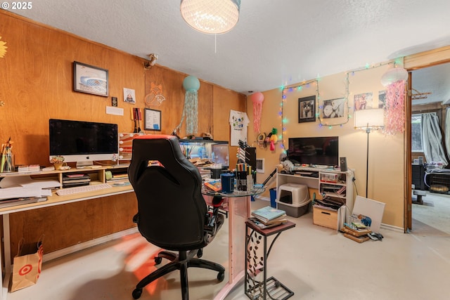 home office featuring a textured ceiling and wood walls