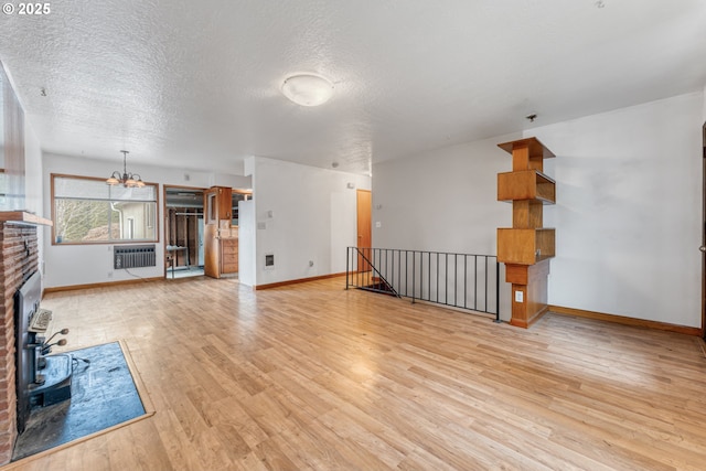 unfurnished living room featuring radiator, a chandelier, a brick fireplace, a textured ceiling, and light hardwood / wood-style flooring