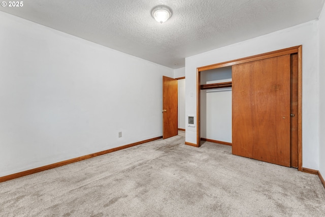 unfurnished bedroom featuring light colored carpet, a closet, and a textured ceiling