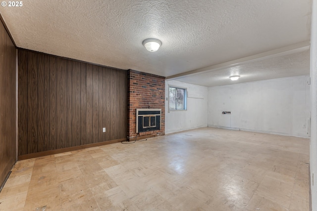 basement featuring a brick fireplace, a textured ceiling, and wood walls