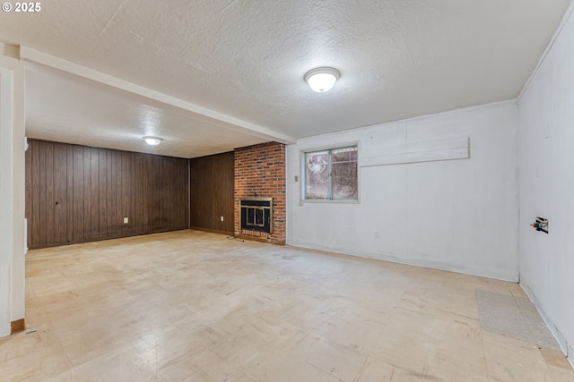 basement with wood walls, a brick fireplace, and a textured ceiling