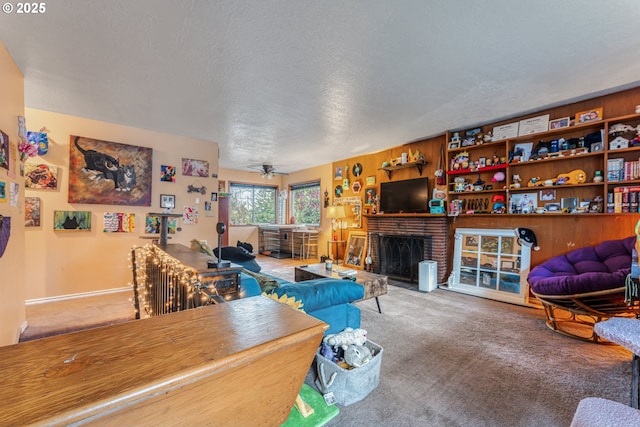 living room with a brick fireplace, ceiling fan, a textured ceiling, and carpet flooring