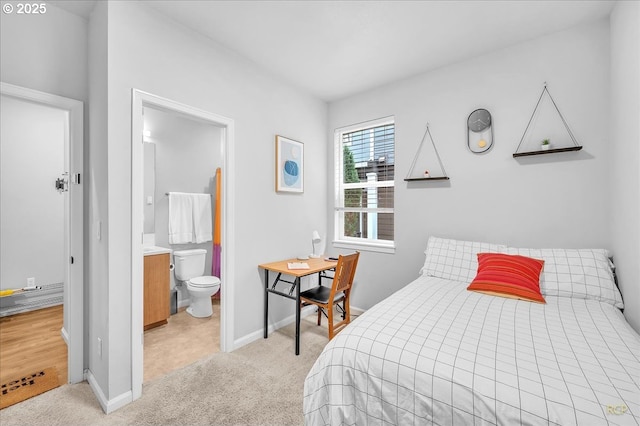 bedroom featuring ensuite bathroom, light carpet, and baseboards