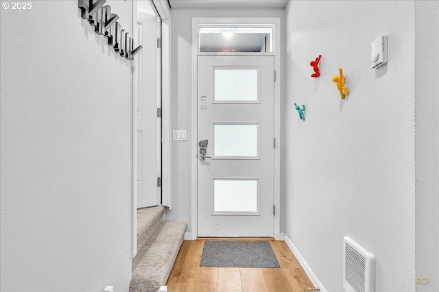doorway to outside with light wood finished floors, visible vents, baseboards, and stairway